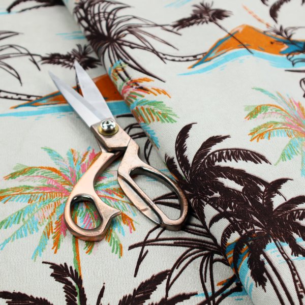 Fabric featuring a vintage-inspired tropical pattern with dark brown line-art palm trees, colourful pastel palm trees, and small orange islands against an off-white background.