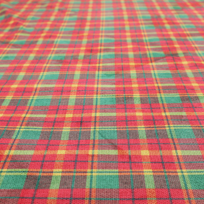 A warm red and green plaid fabric pattern featuring a dense grid of intersecting yellow, dark green, and thin blue stripes.