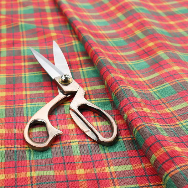 A warm red and green plaid fabric pattern featuring a dense grid of intersecting yellow, dark green, and thin blue stripes.