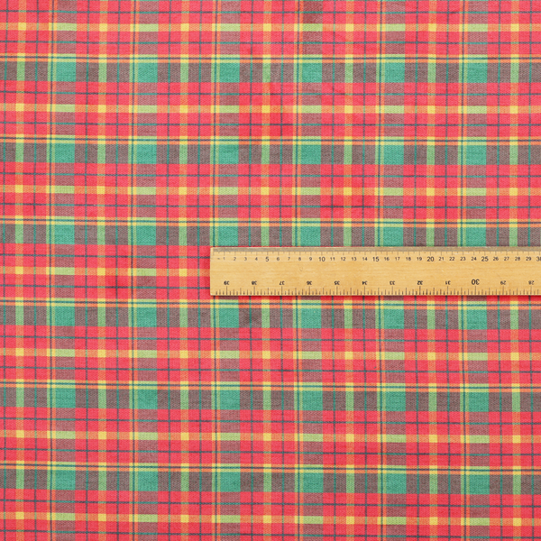 A warm red and green plaid fabric pattern featuring a dense grid of intersecting yellow, dark green, and thin blue stripes.