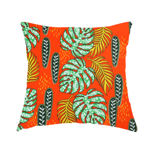 The fabric used to create this handmade cushion features a vibrant, repeating tropical pattern with textured green monstera leaves, yellow ferns, and dark green patterned seed pods on a bright orange background.