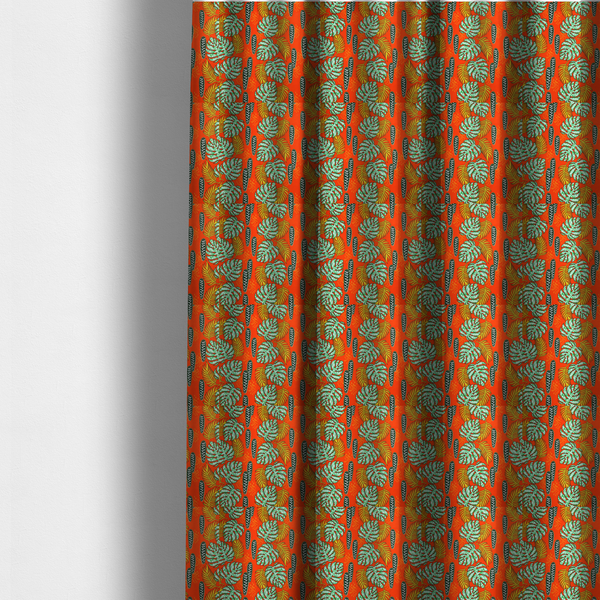 The fabric used to create these made-to-measure curtains features a vibrant, repeating tropical pattern with textured green monstera leaves, yellow ferns, and dark green patterned seed pods on a bright orange background.