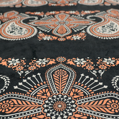 A black fabric pattern featuring elegant horizontal bands of intricate paisley motifs and ornate cross-shaped designs in cream and terracotta orange.