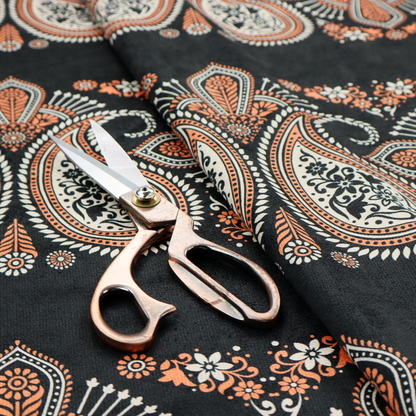 A black fabric pattern featuring elegant horizontal bands of intricate paisley motifs and ornate cross-shaped designs in cream and terracotta orange.