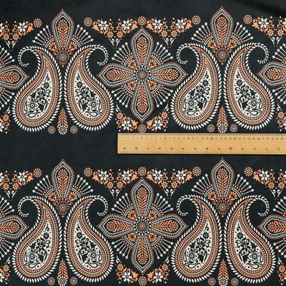 A black fabric pattern featuring elegant horizontal bands of intricate paisley motifs and ornate cross-shaped designs in cream and terracotta orange.