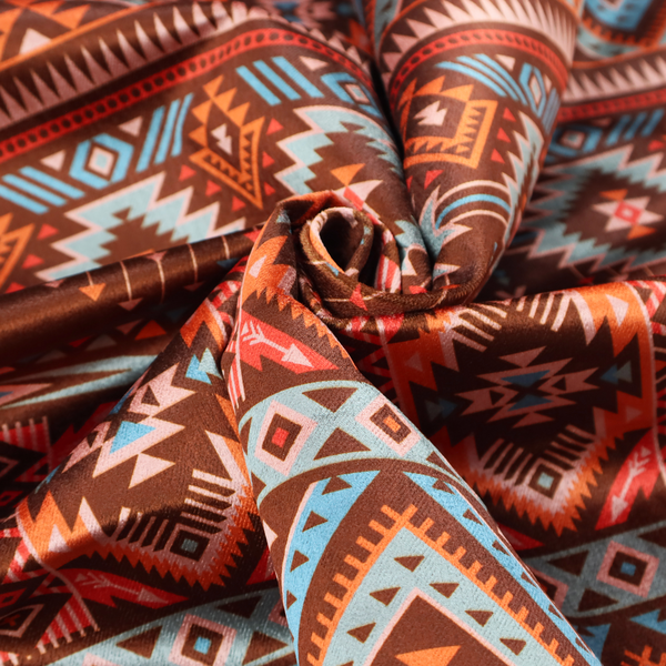 A brown fabric pattern featuring southwest-inspired geometric bands with zigzags, diamonds, and native-style motifs in terracotta, light blue, and cream.