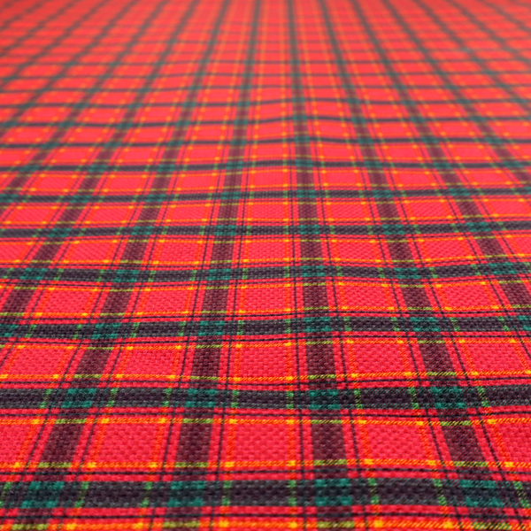 A vibrant red plaid fabric pattern featuring a dense grid of intersecting dark green and thin yellow stripes.
