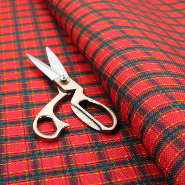 A vibrant red plaid fabric pattern featuring a dense grid of intersecting dark green and thin yellow stripes.