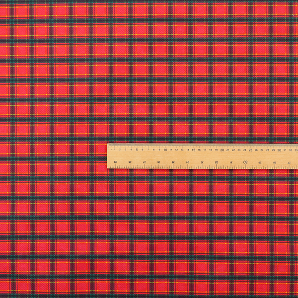 A vibrant red plaid fabric pattern featuring a dense grid of intersecting dark green and thin yellow stripes.