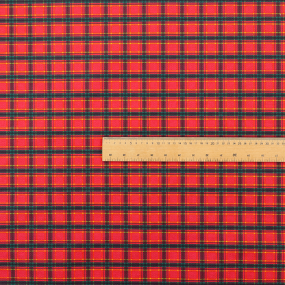A vibrant red plaid fabric pattern featuring a dense grid of intersecting dark green and thin yellow stripes.