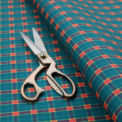 A rich teal plaid fabric pattern featuring a dense grid of intersecting dark blue and thin yellow stripes with bright red square accents.