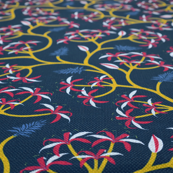 A deep blue fabric pattern featuring a winding trail of bright yellow vines accented with clusters of pink and white flowers and blue fern leaves.