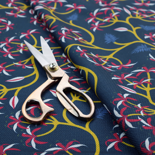 A deep blue fabric pattern featuring a winding trail of bright yellow vines accented with clusters of pink and white flowers and blue fern leaves.