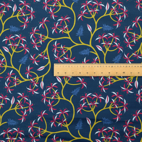 A deep blue fabric pattern featuring a winding trail of bright yellow vines accented with clusters of pink and white flowers and blue fern leaves.