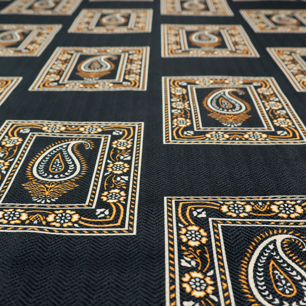 Fabric featuring a traditional repeating pattern of detailed white and gold paisley motifs, each enclosed within an ornate rectangular border on a charcoal black background.