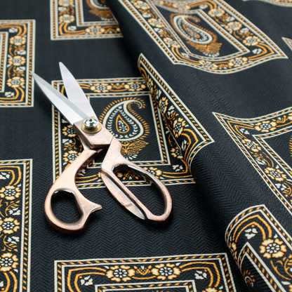 Fabric featuring a traditional repeating pattern of detailed white and gold paisley motifs, each enclosed within an ornate rectangular border on a charcoal black background.