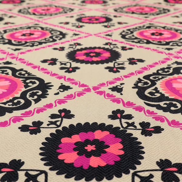 Fabric featuring a vibrant bohemian Suzani-style pattern with bold hot pink and black floral medallions arranged in a diamond lattice on a cream background.