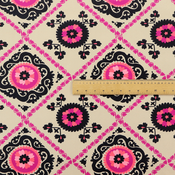 Fabric featuring a vibrant bohemian Suzani-style pattern with bold hot pink and black floral medallions arranged in a diamond lattice on a cream background.