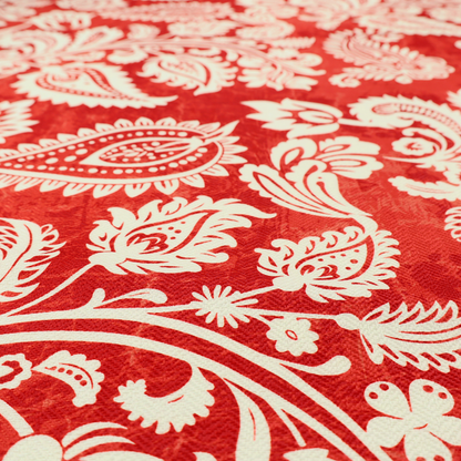 Fabric featuring an ornate repeating pattern of elegant ivory paisley motifs and botanical flourishes over a textured, mottled crimson red background.