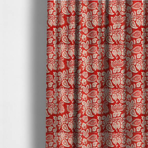 The fabric used to create these made-to-measure curtains is a featuring an ornate repeating pattern of elegant ivory paisley motifs and botanical flourishes over a textured, mottled crimson red background.