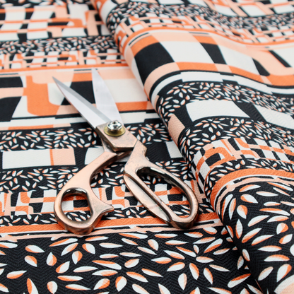 Fabric featuring a bold, multi-patterned horizontal striped design with alternating bands of geometric coral and cream blocks and dense black-and-white micro leaf speckles.