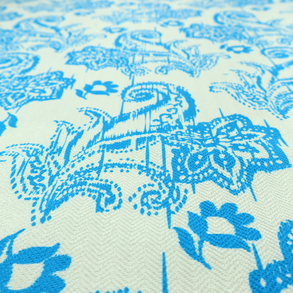 A bohemian-style textile featuring a bold ikat paisley pattern printed against a crisp off-white backdrop. The repeating motif showcases large, ornate teardrop paisley swirls integrated with stylized damask flowers.
