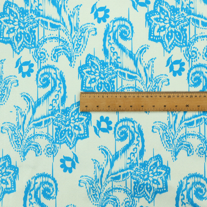 A bohemian-style textile featuring a bold ikat paisley pattern printed against a crisp off-white backdrop. The repeating motif showcases large, ornate teardrop paisley swirls integrated with stylized damask flowers.