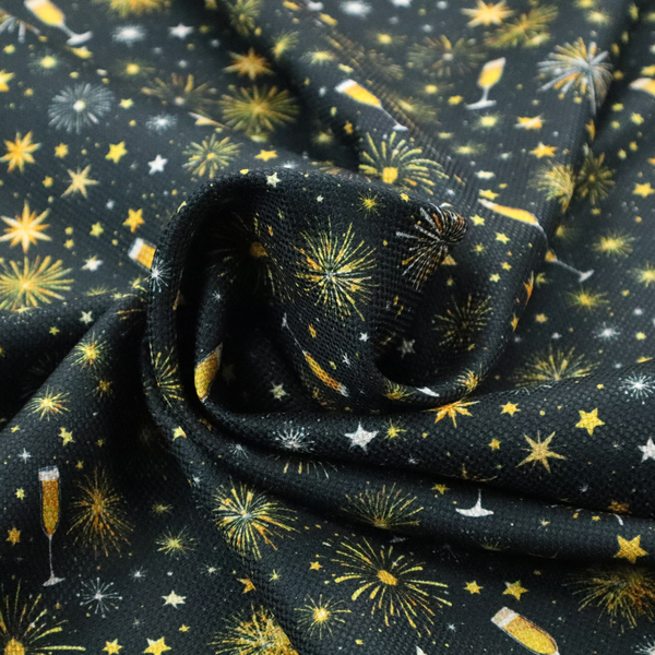 Fabric featuring a festive celebration print with an all-over micro pattern of golden champagne glasses, bursting fireworks, and twinkling stars on a deep black background.