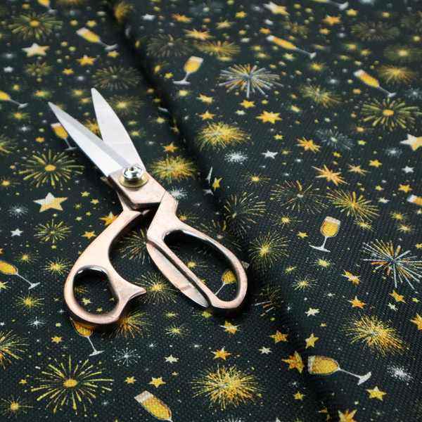 Fabric featuring a festive celebration print with an all-over micro pattern of golden champagne glasses, bursting fireworks, and twinkling stars on a deep black background.