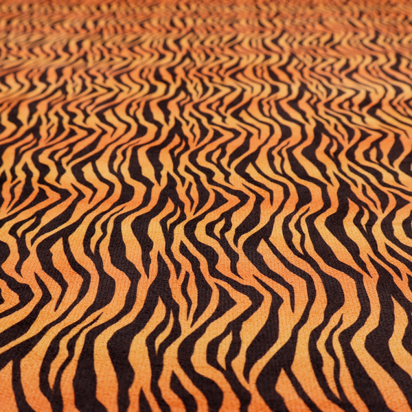 Fabric featuring a dense, repeating animal print pattern of vertical black tiger stripes over a vibrant orange background.