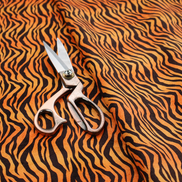 Fabric featuring a dense, repeating animal print pattern of vertical black tiger stripes over a vibrant orange background.