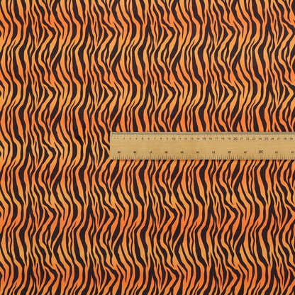 Fabric featuring a dense, repeating animal print pattern of vertical black tiger stripes over a vibrant orange background.