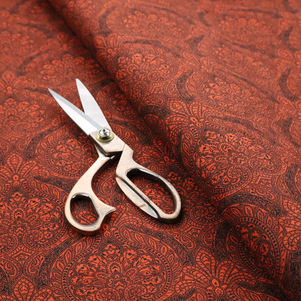 An intricate, repeating damask and paisley design on fabric, featuring elegant, symmetrical motifs.
