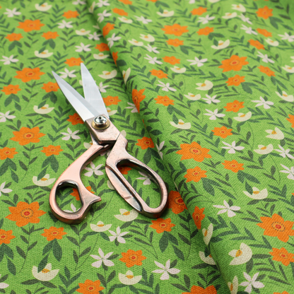 A bright green fabric featuring a dense, repeating pattern of small orange flowers, delicate white blossoms, and dark green leaves.
