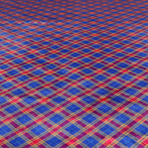 Vibrant blue and red diamond plaid fabric featuring an intricate diagonal checked pattern with intersecting lines in rich royal blue, bright red, and yellow highlights.