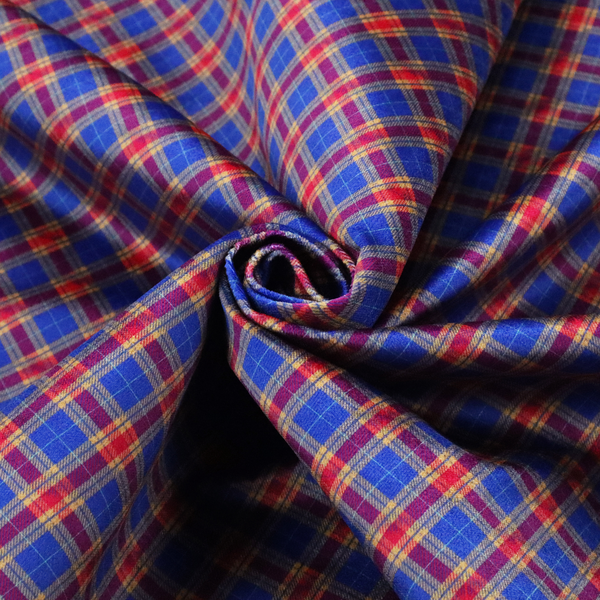 Vibrant blue and red diamond plaid fabric featuring an intricate diagonal checked pattern with intersecting lines in rich royal blue, bright red, and yellow highlights.