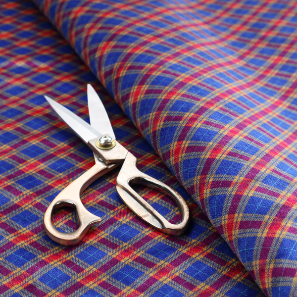 Vibrant blue and red diamond plaid fabric featuring an intricate diagonal checked pattern with intersecting lines in rich royal blue, bright red, and yellow highlights.