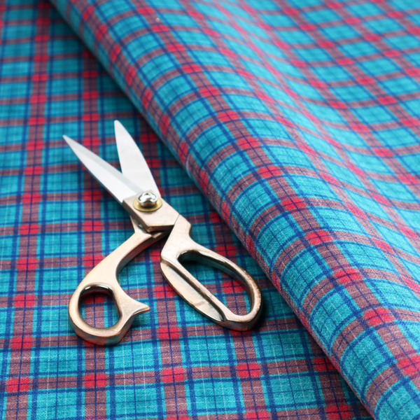 Bright turquoise and red plaid fabric featuring a classic checked pattern with intersecting lines in rich turquoise, vibrant red, and dark blue accents.