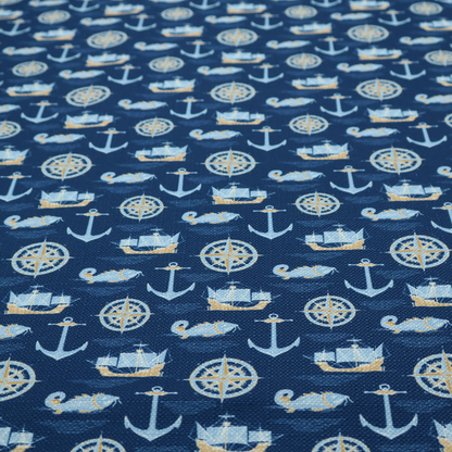 A nautical-themed fabric pattern featuring alternating rows of light blue and gold sailing ships, compass roses, anchors, and fish against a dark blue background.
