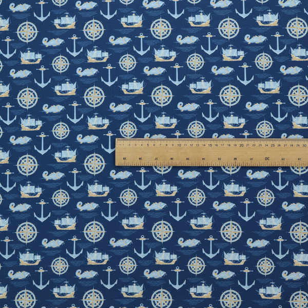 A nautical-themed fabric pattern featuring alternating rows of light blue and gold sailing ships, compass roses, anchors, and fish against a dark blue background.