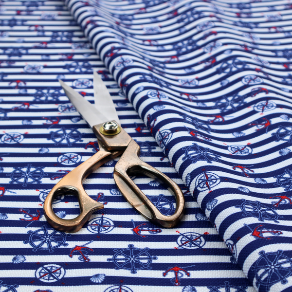 A nautical-themed fabric pattern featuring alternating horizontal stripes of navy blue and light blue, scattered with small dark blue ship's wheels, red anchors, and compass roses.