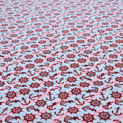 A nautical-themed fabric pattern featuring diagonal stripes in light blue and pink, scattered with dark red ship's wheels and anchors.