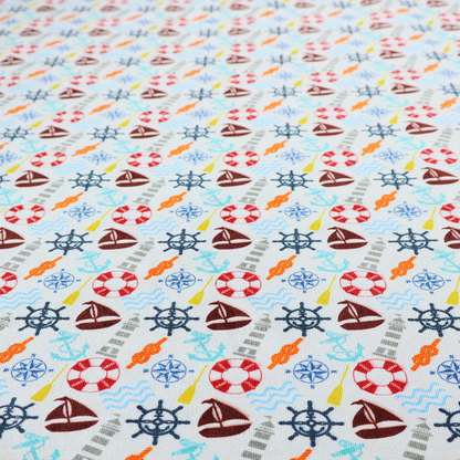 A colourful nautical-themed fabric pattern featuring a repeating mix of lighthouses, sailboats, life rings, ship's wheels, anchors, and waves against a white background.