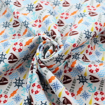 A colourful nautical-themed fabric pattern featuring a repeating mix of lighthouses, sailboats, life rings, ship's wheels, anchors, and waves against a white background.