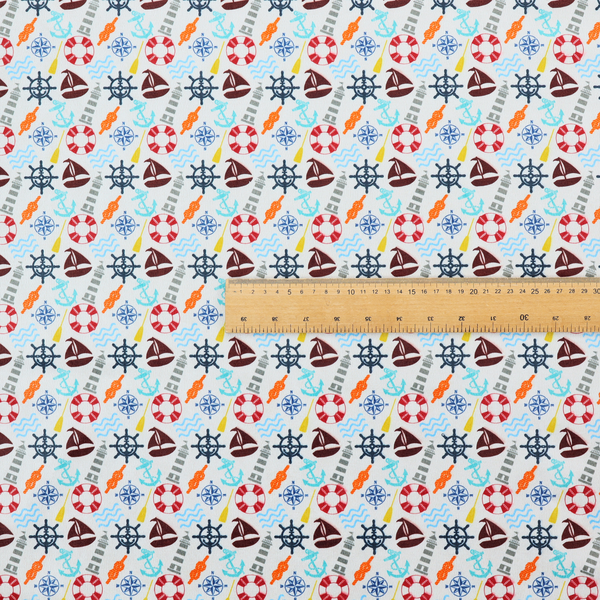 A colourful nautical-themed fabric pattern featuring a repeating mix of lighthouses, sailboats, life rings, ship's wheels, anchors, and waves against a white background.