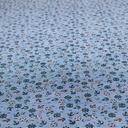 The pattern features a nautical theme filled with tiny ships' steering wheels, anchors, and lifebuoys scattered across the fabric.