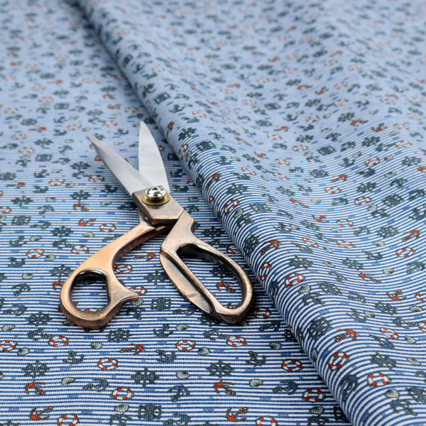 The pattern features a nautical theme filled with tiny ships' steering wheels, anchors, and lifebuoys scattered across the fabric.