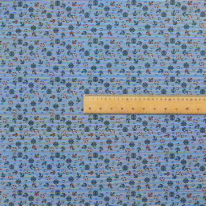 The pattern features a nautical theme filled with tiny ships' steering wheels, anchors, and lifebuoys scattered across the fabric.