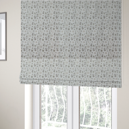 The fabric used to create these Roman blinds is a pattern features a nautical-themed collage containing lighthouses, sailing ships, anchors, compass roses, seashells, steering wheels, ship bells, and marlin fish.