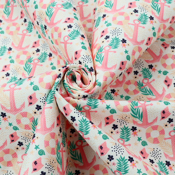 A light mint green fabric with a repeating nautical pattern featuring pink anchors framed by teal palm fronds, interspersed with pink and white striped life rings, tiny dark blue flowers, and small coral shells.